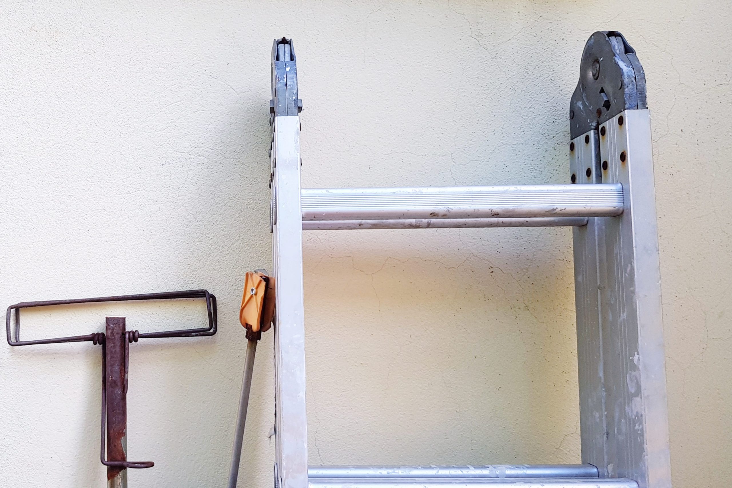 Old rusty stainless steel mop with Aluminum ladder or staircase leaning against on white cement wall with copy space - Vintage object, Equipment and Cleaning tool concept