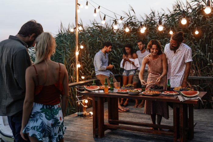 Group of young men and women enjoying summer holiday at outdoor party.