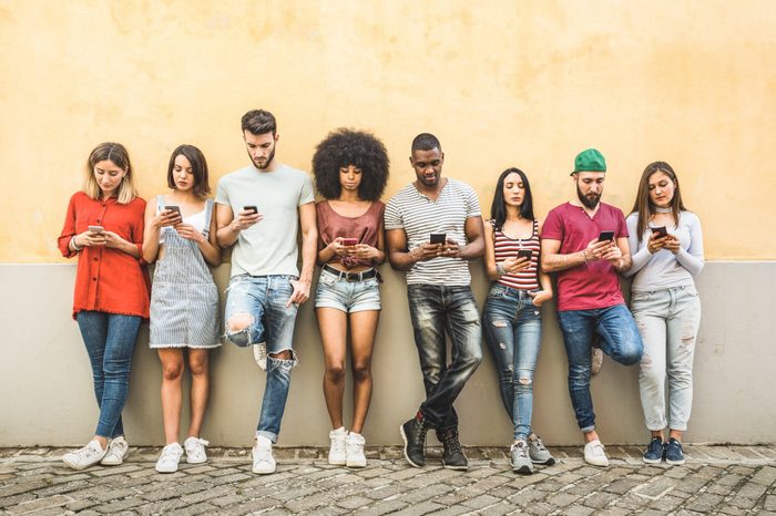 Multiracial friends using smartphone against wall at university college backyard - Young people addicted by mobile smart phone - Technology concept with always connected millennials - Filter image