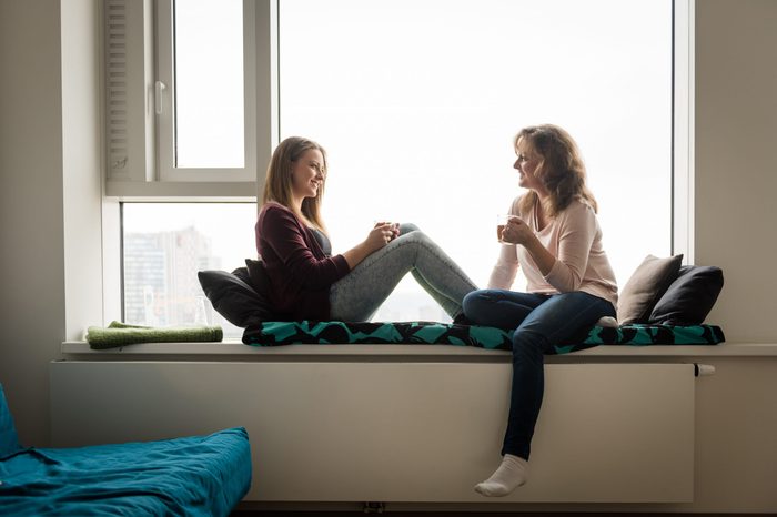 Daughter and mother having tea together, facing each other.