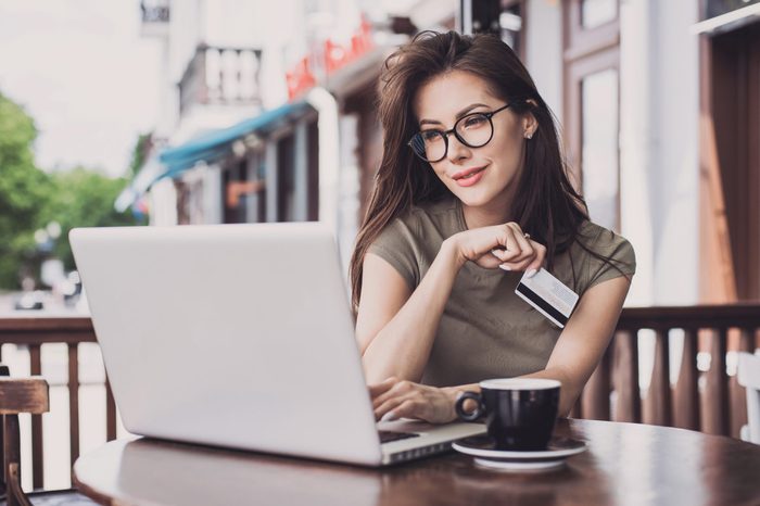 Young woman holding credit card and using laptop computer. Online shopping concept