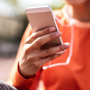 Music for relax. Close up image sport woman using smart phone. Focus on hand.