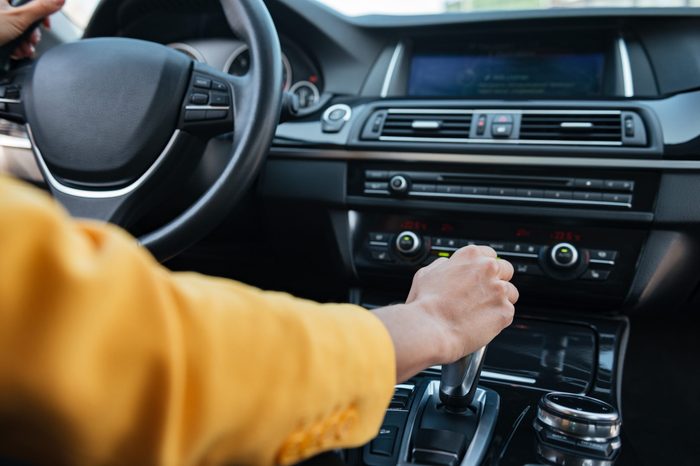 Close up of hand of female driver shifting gear stick before driving car