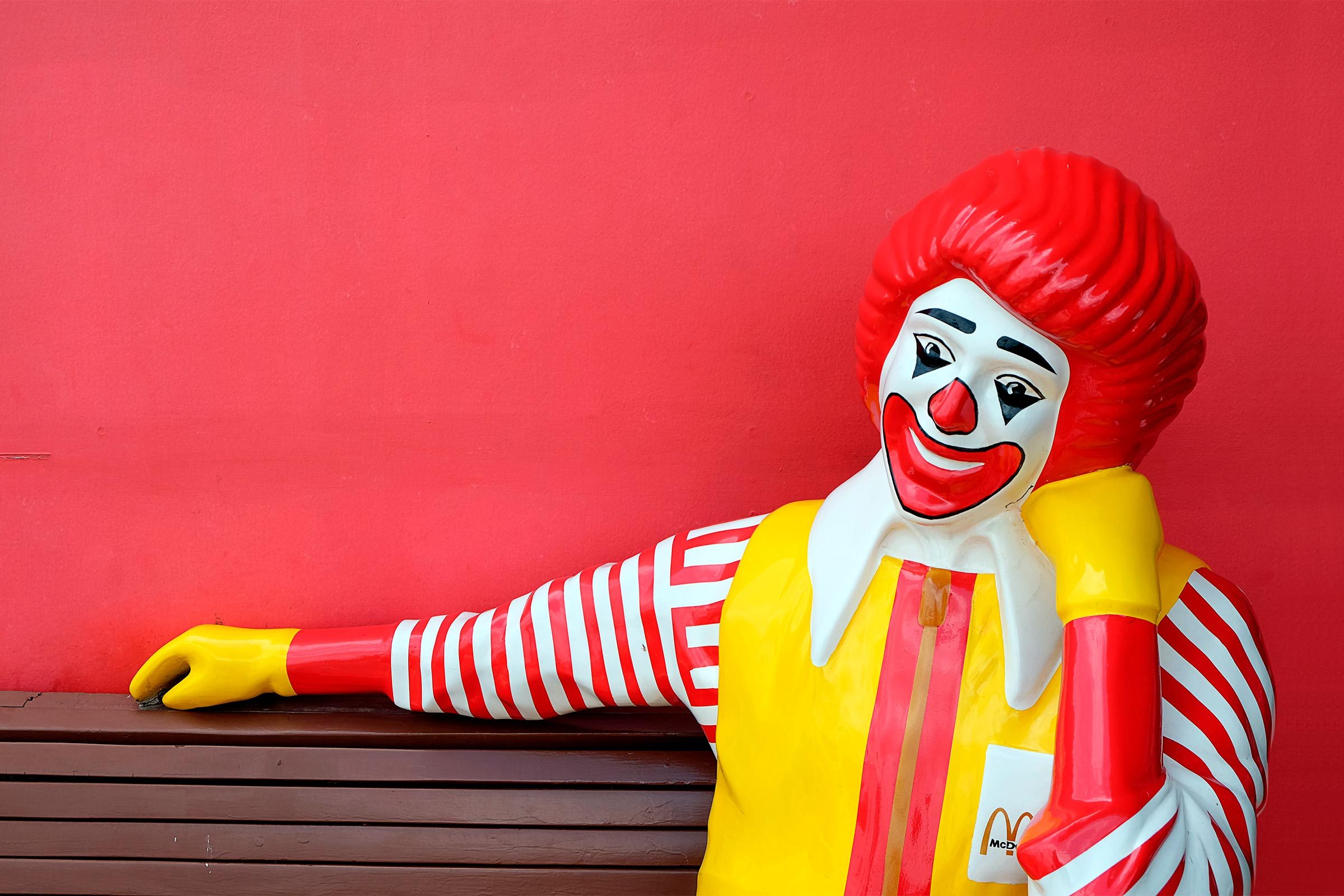 ronald mcdonald statue sitting on a bench at mcdonalds