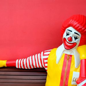 ronald mcdonald statue sitting on a bench at mcdonalds