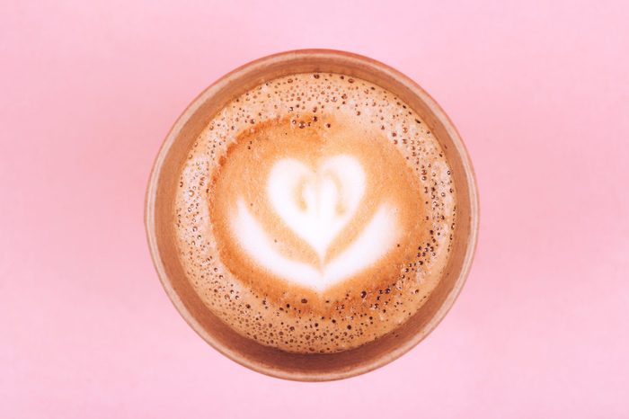 Paper cup of coffee to go on pink trendy pastel background from above, flat lay