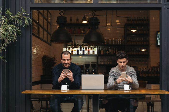 Friends using mobile and laptop in a coffee shop.