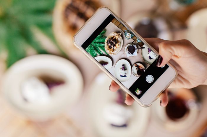 Woman taking photo of dishes at the cafe. Breakfast, social media, blogger's life, outdoors.