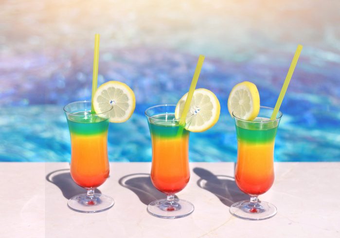 Poolside red cocktail served cold at pool bar at sunny summer day. Summer holidays, travel, people and vacation concept.