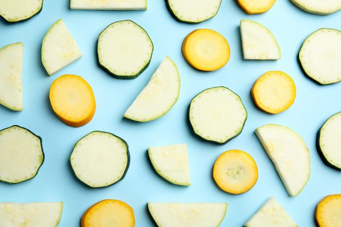 Fresh ripe cut zucchinis on light blue background, flat lay