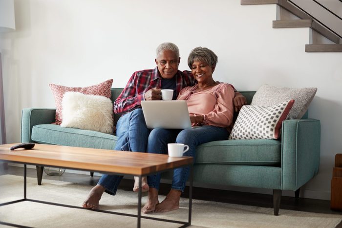 Senior Couple Sitting On Sofa At Home Using Laptop To Shop Online