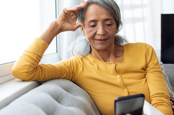 Front view of African American Woman using smartphone. Authentic Senior Retired Life Concept