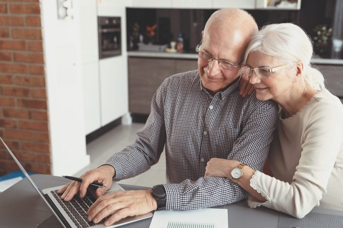 Senior couple paying bills together on laptop. Couple doing some paperwork and calculations at home