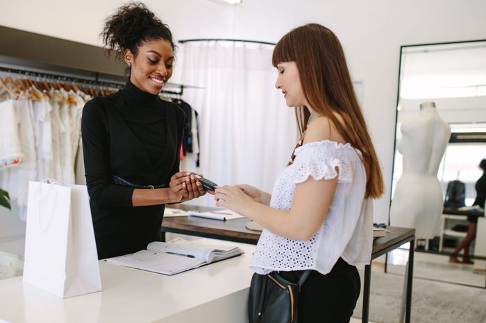 Customer shopping designer wear at a fashion boutique. Customer making payment using a credit card on a point of sale machine.