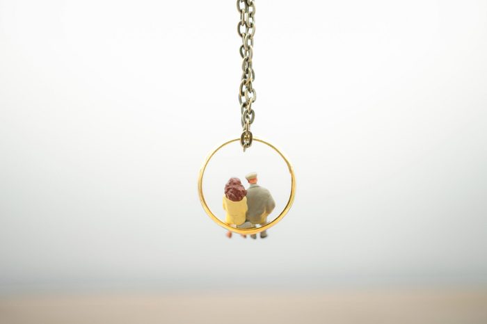 Miniature people: Couple sitting on gold ring