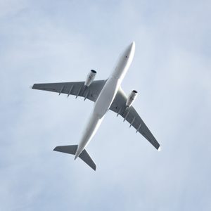 Travel, transportation, aviation concept, copy space/ Wide-body passenger airplane  flying overhead against a spring blue sky, bottom view