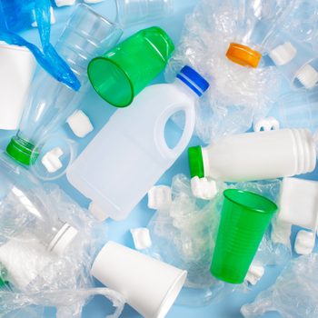 Various plastic garbage on the light blue background, problem of waste sorting and utilisation