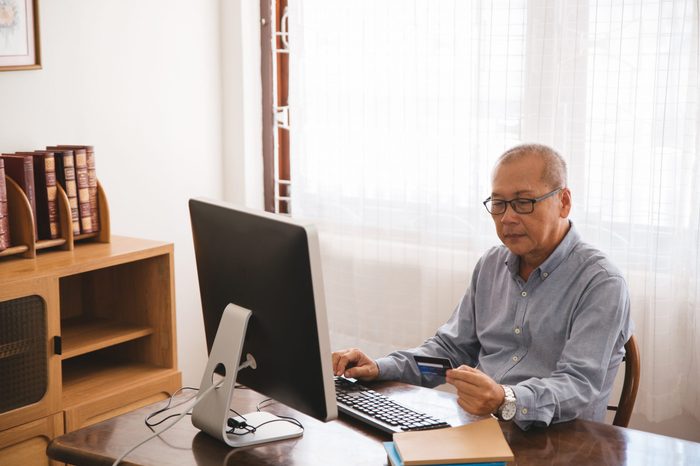 Senior man shopping online using computer and credit card.