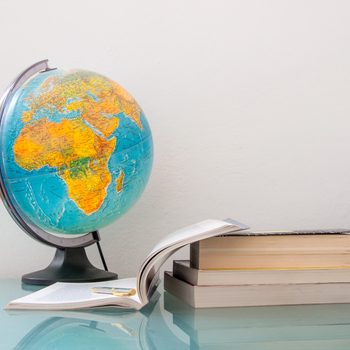 desk with a pile of  books and school supplies like pencils and stationery and world map globe, back to school college university education concept, homework classroom study