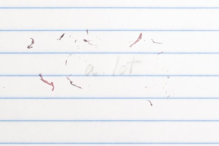 erased text "a lot" with eraser shavings on loose leaf paper