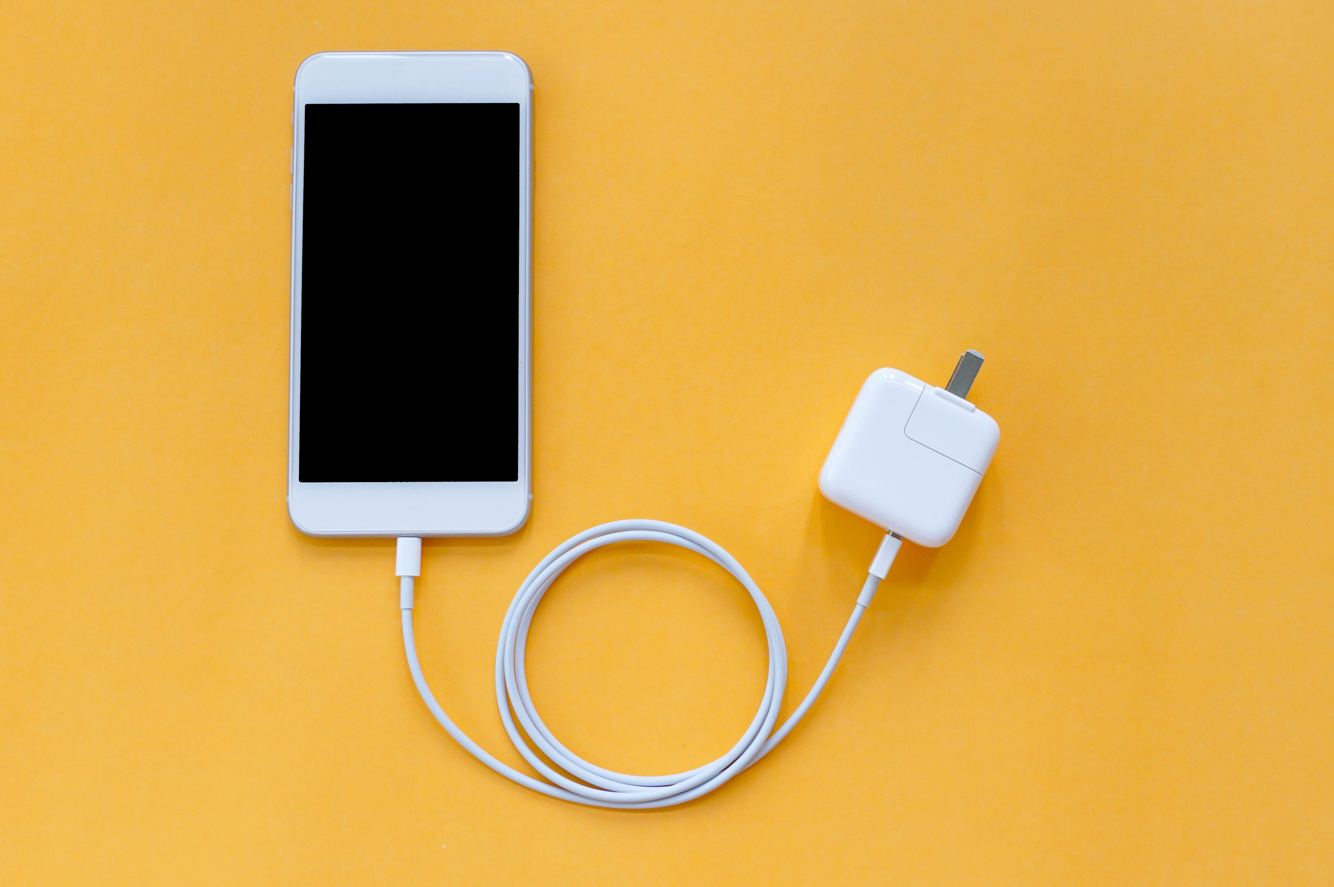 Smartphone Is Connected to Fast Charger Adapter through USB Cable on Orange Background Top View