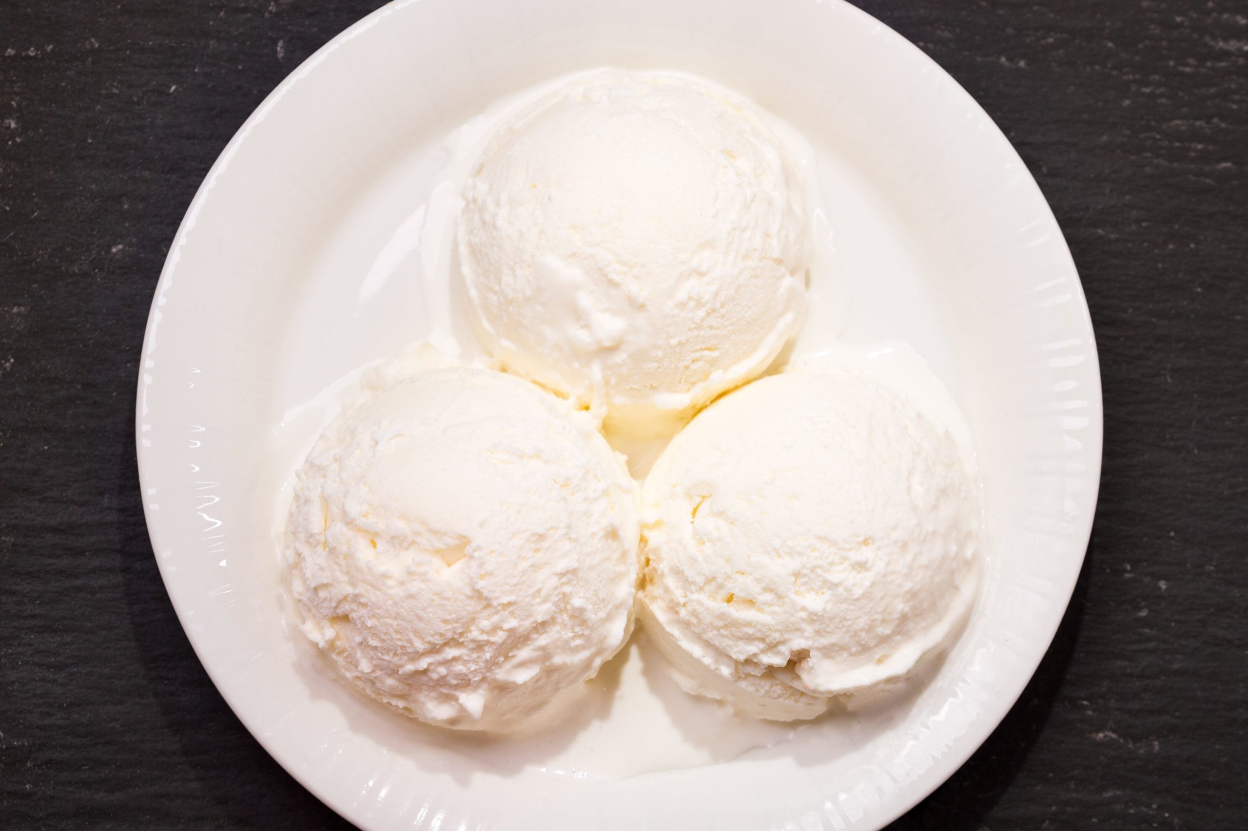 Plate of ice cream scoops and waffle cones on dark background. Top view with copy space, banner