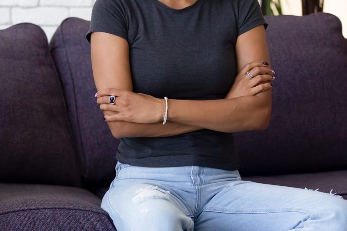 Close up African American couple ignore each other after quarrel, sitting with arms crossed on sofa at home, unhappy wife and husband avoid talking, family conflict concept, relationship problem