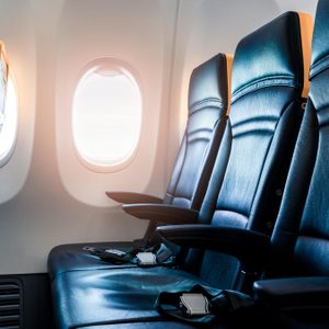 Plane interior - cabin with modern leather chair for passenger of airplane. Aircraft seats and window. - Horizontal image