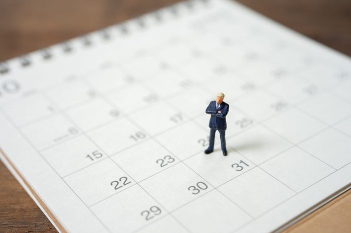 Miniature people businessmen standing on white calendar using as background business concept and finance concept with copy space for your text or design.