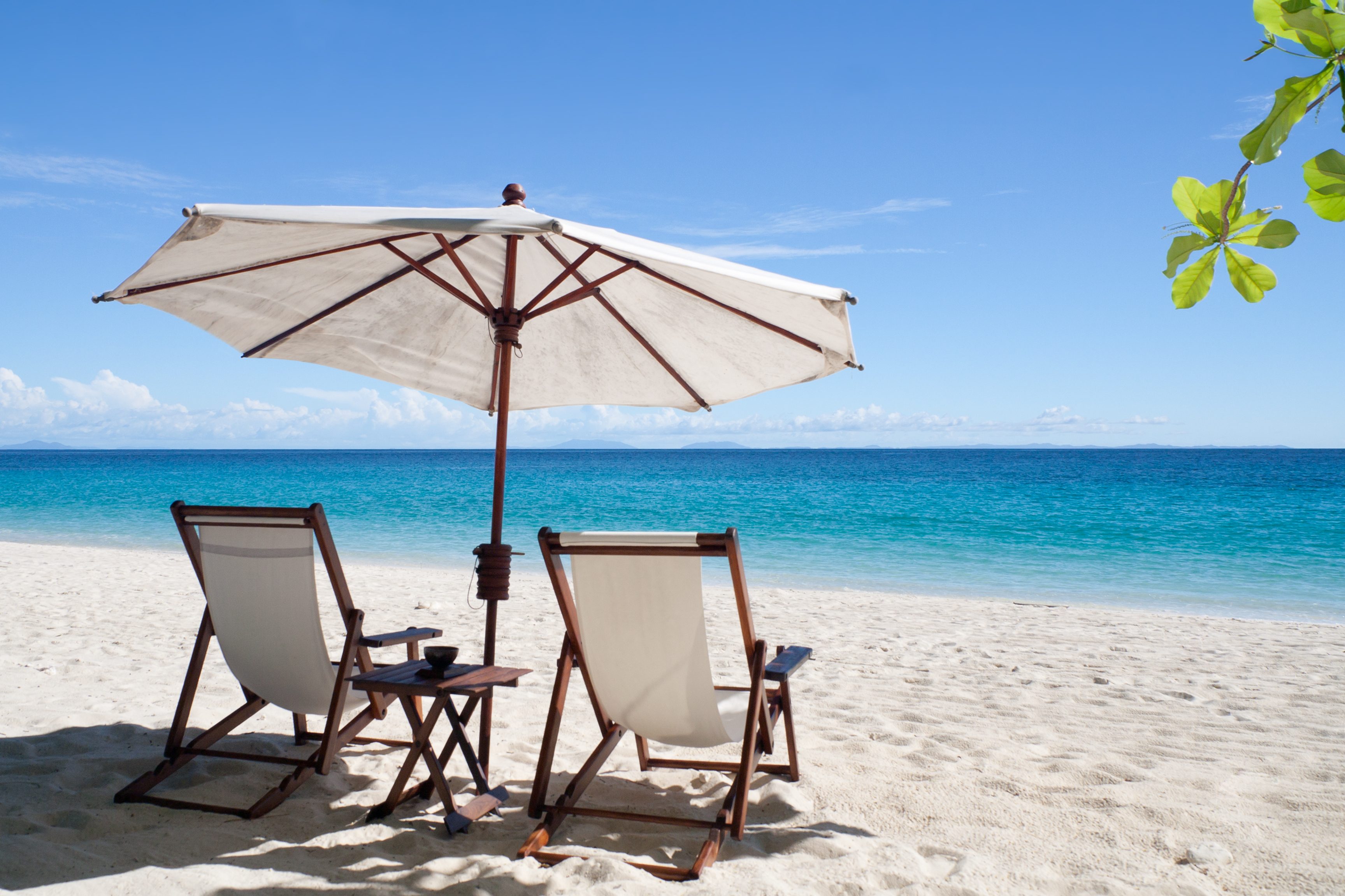 Deckchairs and parasol on the white sand beach facing the lagoon