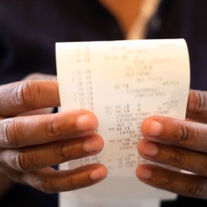 Black Woman Holding Receipt and looking over the purchases