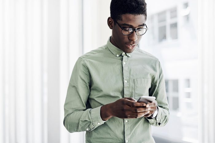 young man texting near an open window