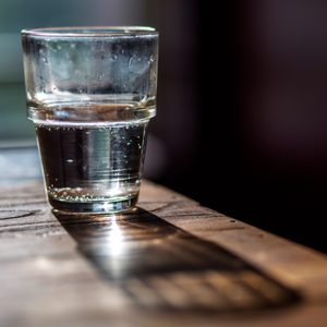 water glass on a wooden table nightstand in the morning light