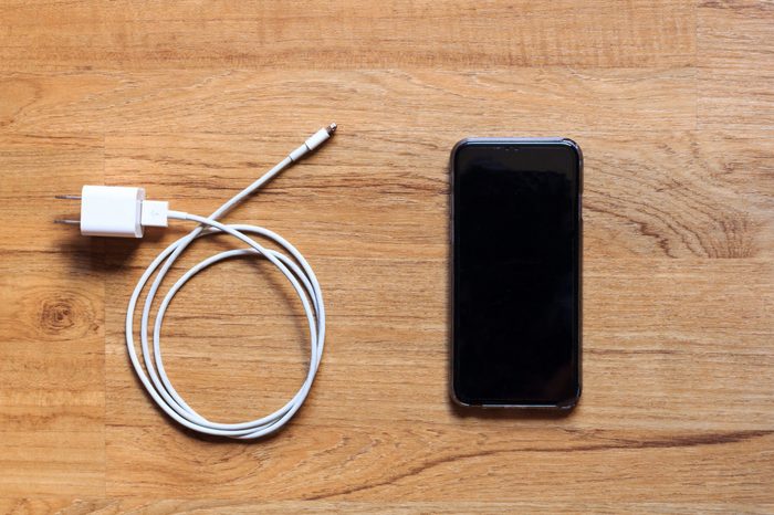 Cable phone chargers and mobile phone on wood background, Top view.