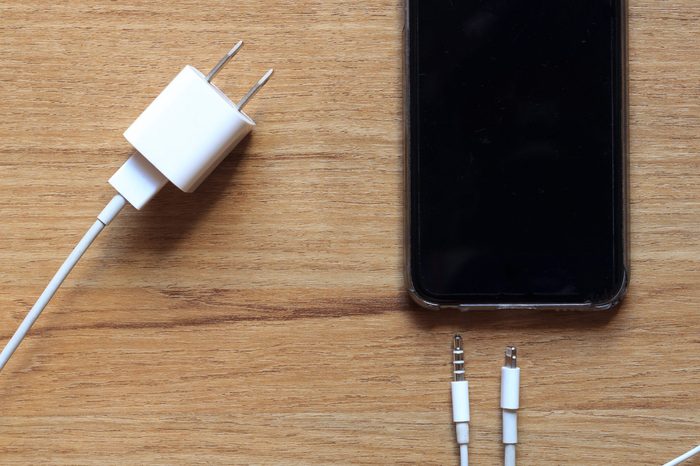 Cable phone chargers, Earphone and mobile phone on wood background, Top view.