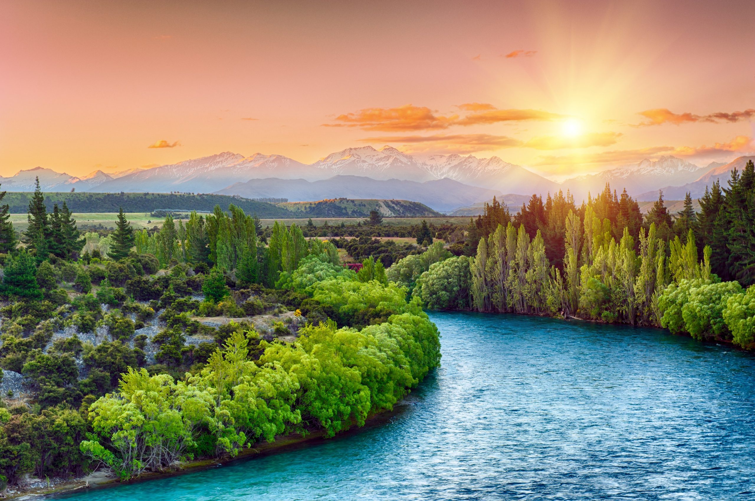 Beautiful sunset over the bend of the river Clutha with Southern Alps peaks on the horizon, New Zealand