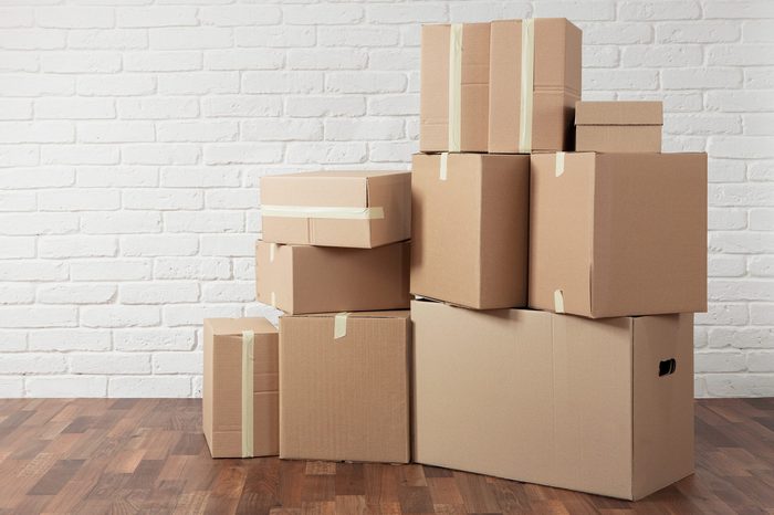 Moving in. Stack of cardboard boxes in the empty room with copy space