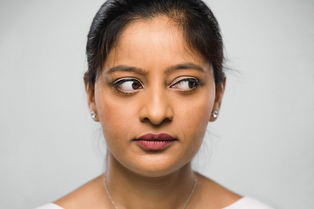 close up of woman's face and eyes. looking to the side. gray background.