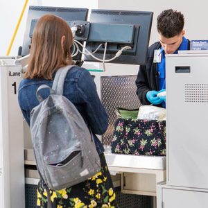 woman watching as a tsa agent searches her bag