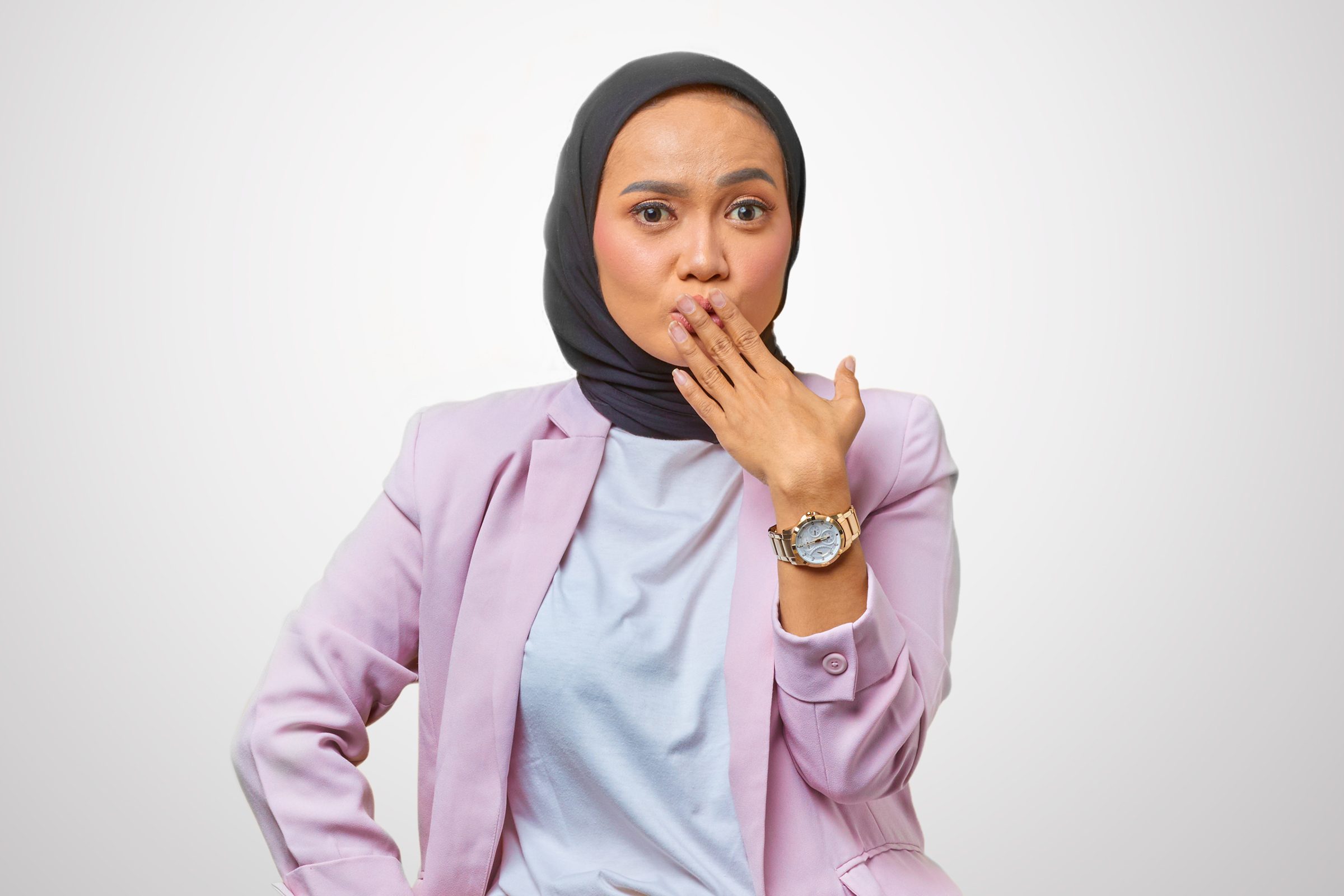 studio portrait of a woman covering her mouth