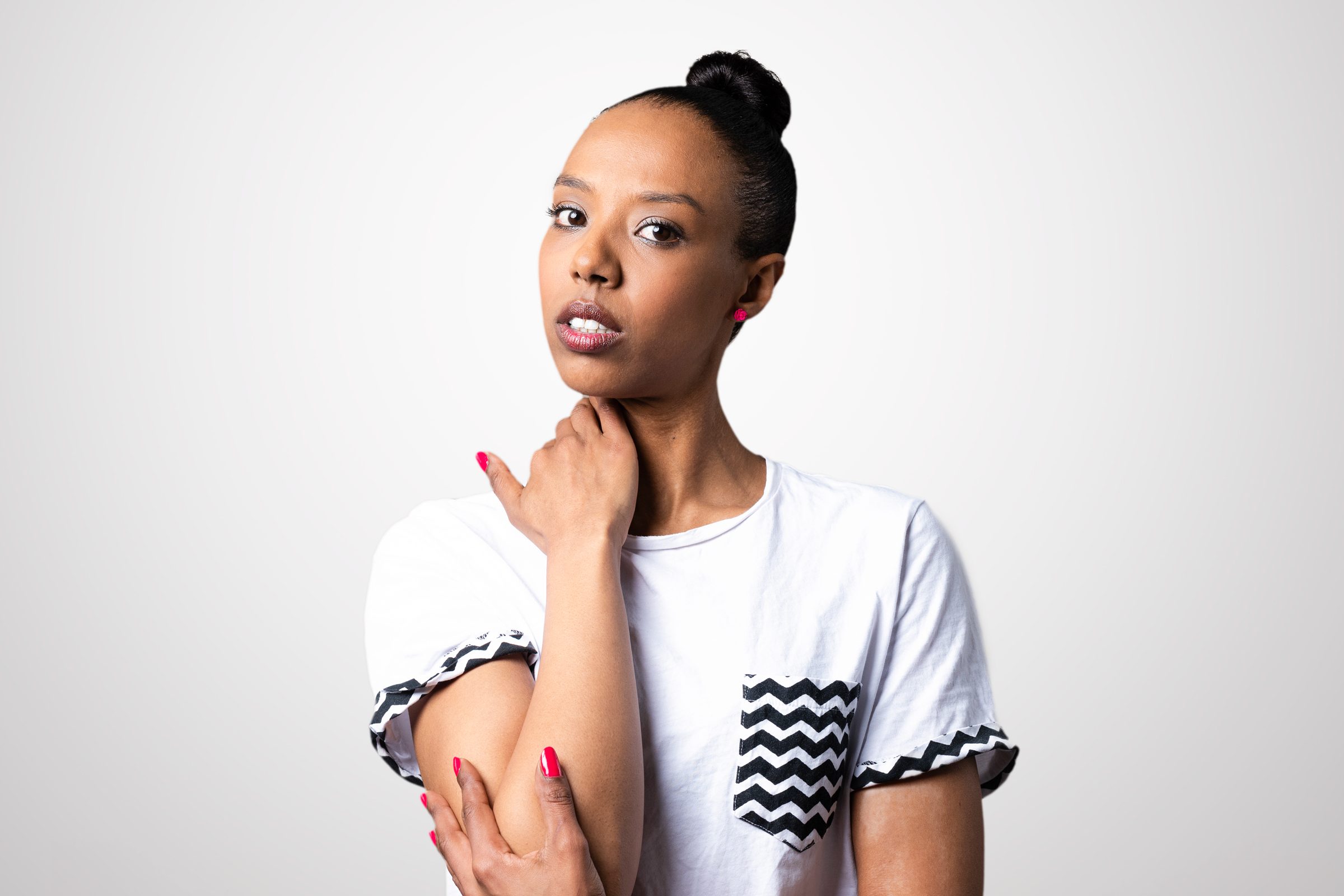 studio shot of a woman looking pensive with her one hand on her shoulder