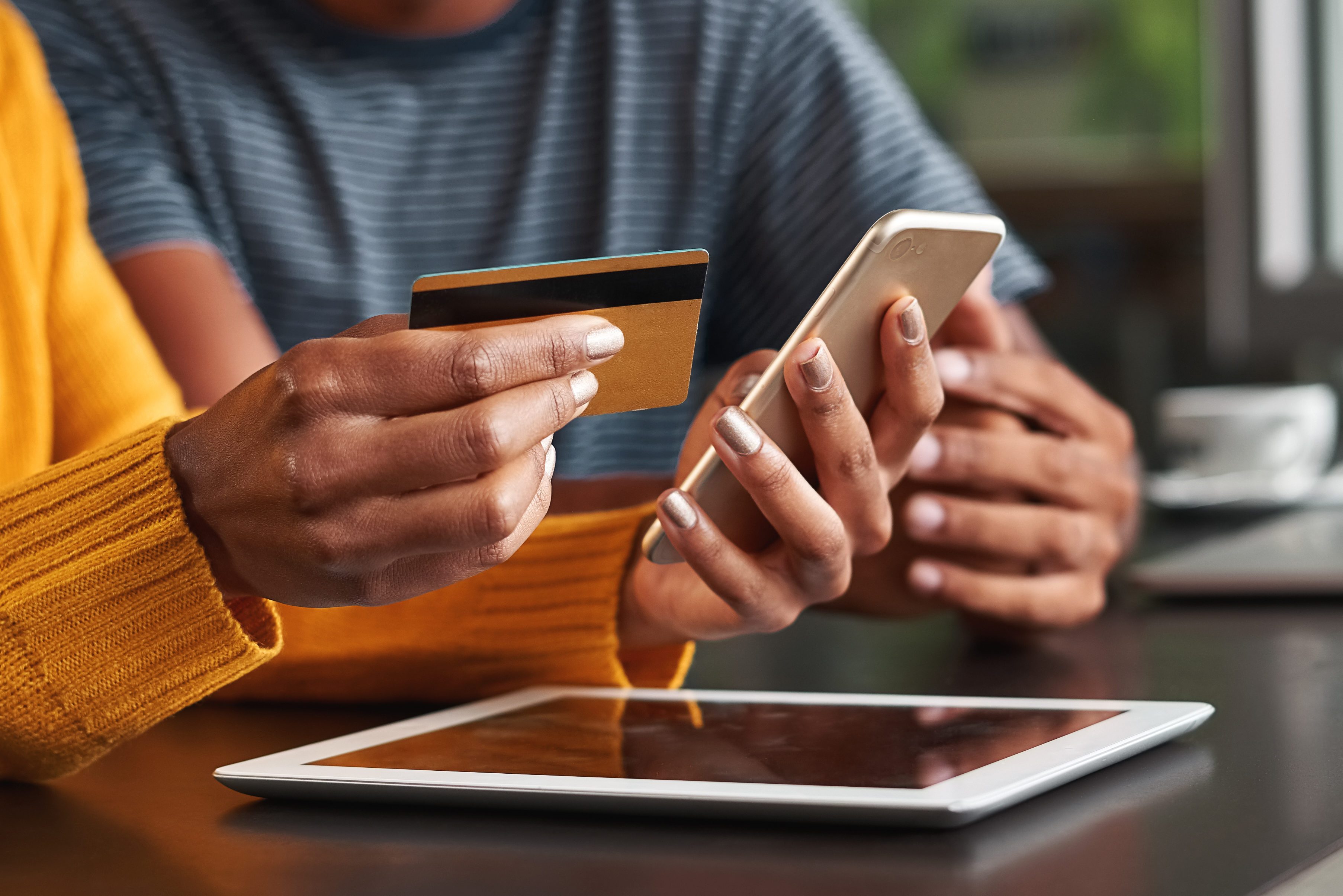 Woman in cafe holding credit card and mobile phone