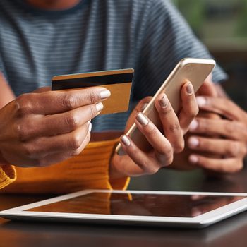 Woman in cafe holding credit card and mobile phone