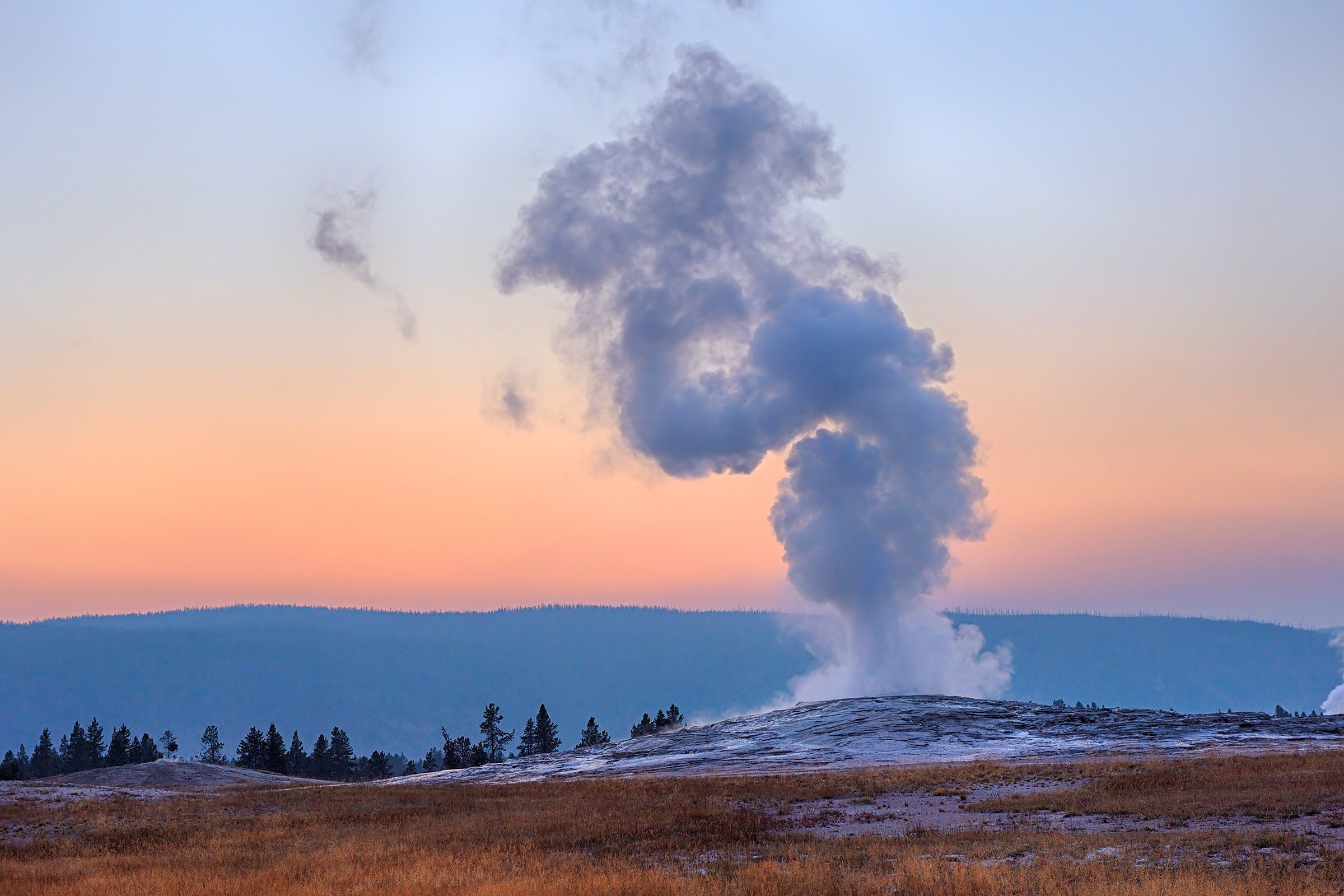 USA, Wyoming, Yellowstone National Park, Old Faithful Geyser erupting at sunset