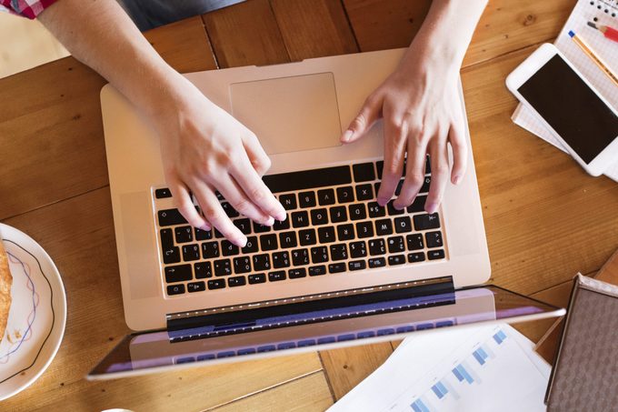 Unrecognizable young woman at home, working on laptop, studying