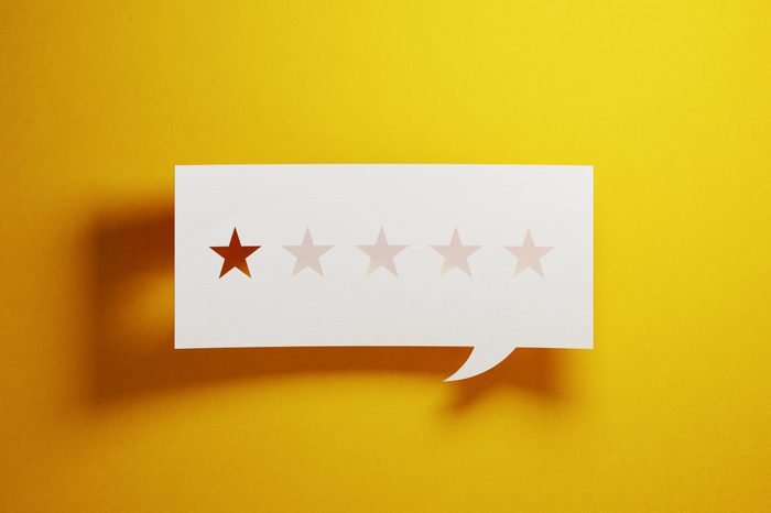 Feedback Concept - White Chat Bubble With Cut Out Star Shapes Over Yellow Background