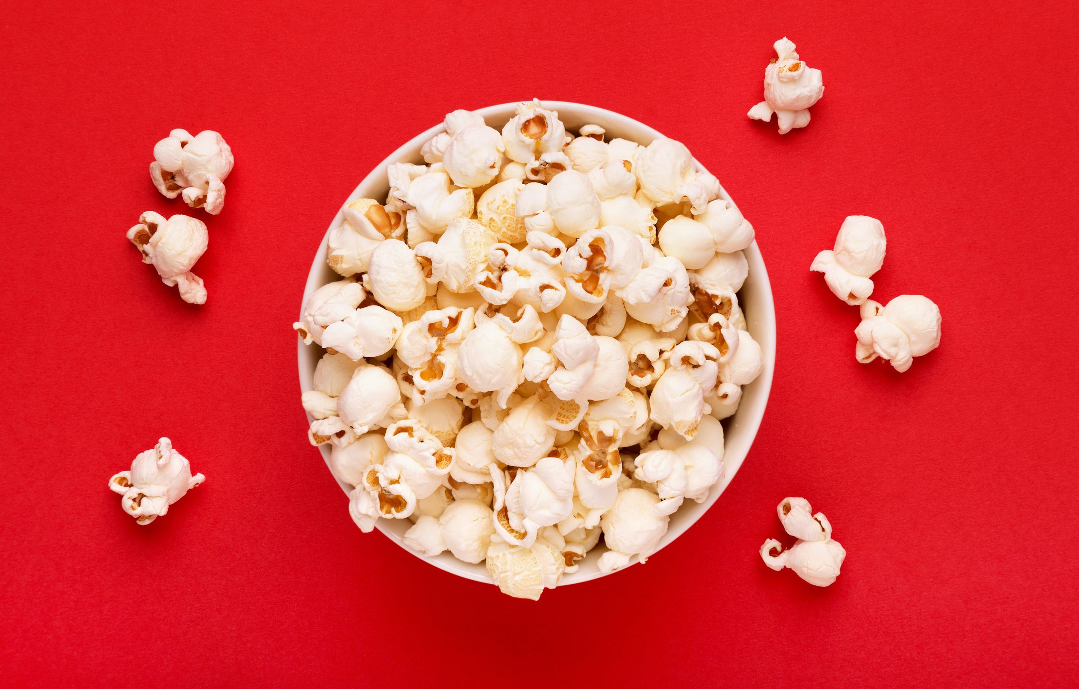 Directly Above Shot Of Popcorns In Bowl Against Red Background