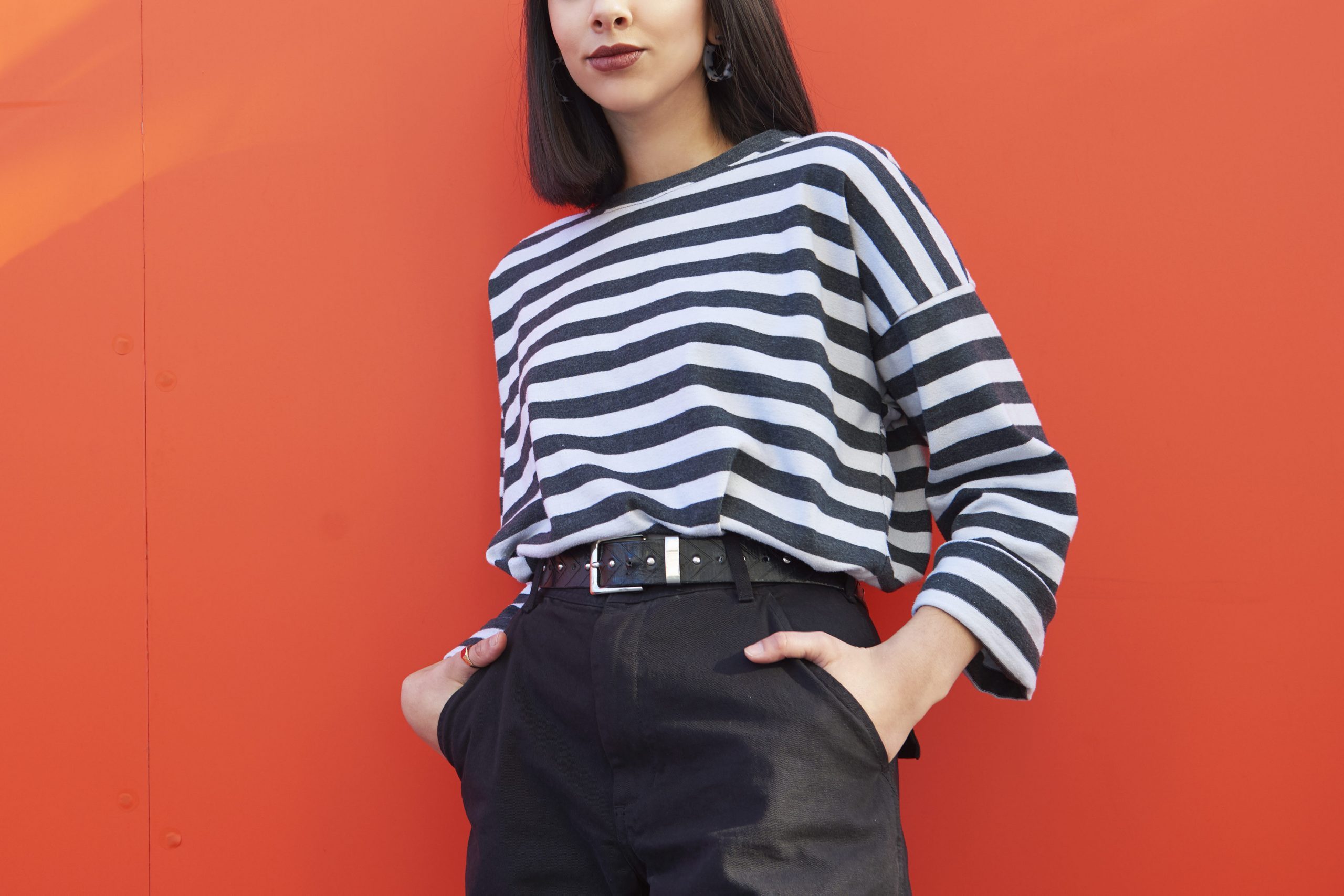 Portrait of young woman standing against red background.