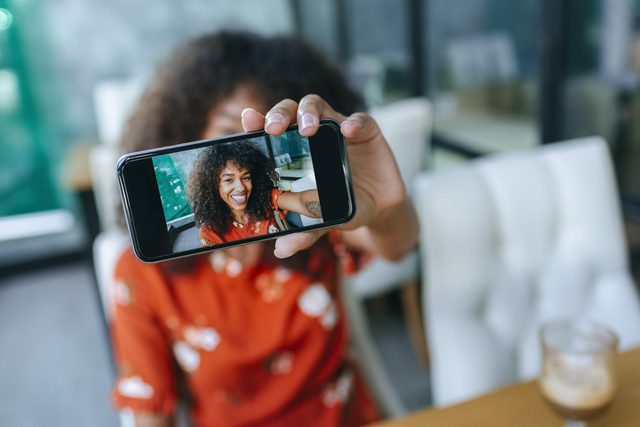 Smiling young woman taking selfie with smartphone, close-up