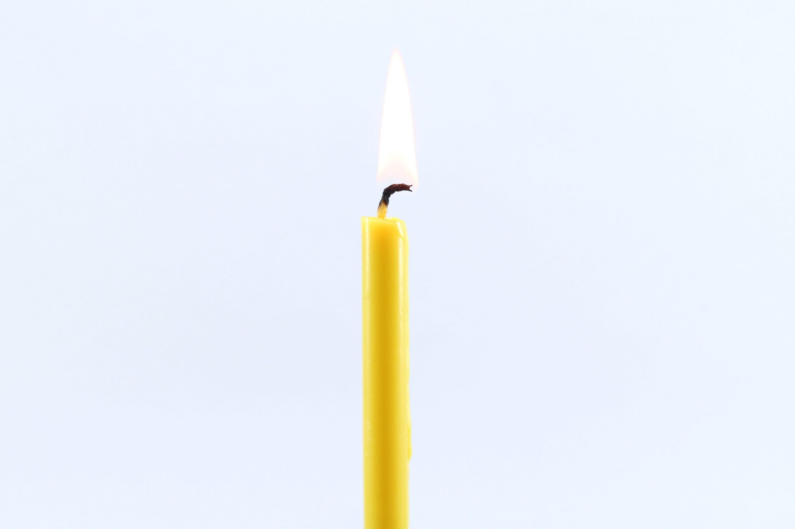 Close-Up Of Burning Candle Against White Background